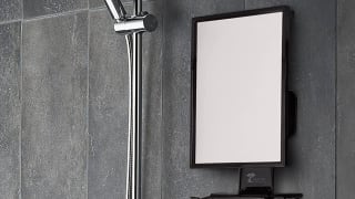 A fogless shower mirror being used for music and for a man to shave.