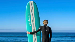 A guy taking his board into the ocean to surf.