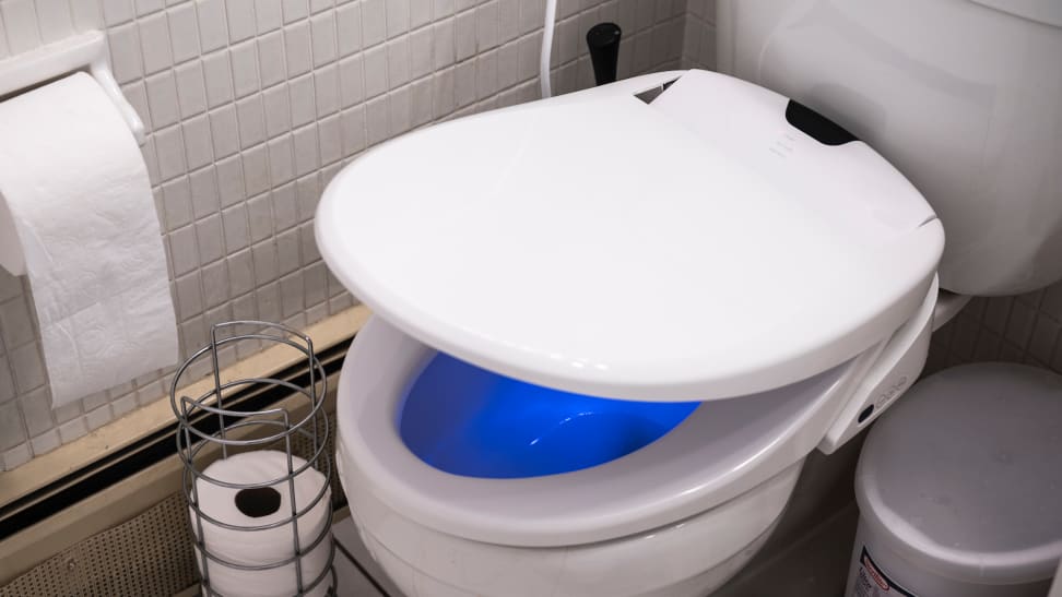 A bidet attachment on a toilet. The bowl glows mysteriously blue.