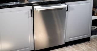 A close-up shot of a stainless steel dishwasher installed into a kitchen cabinet.