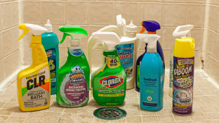 An array of shower cleaners, situated in a small shower around a drain.