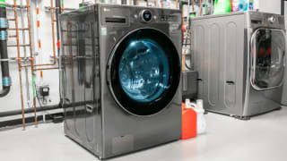 An LG washer-dryer combo in the Reviewed testing lab in front of a wall of copper pipes.