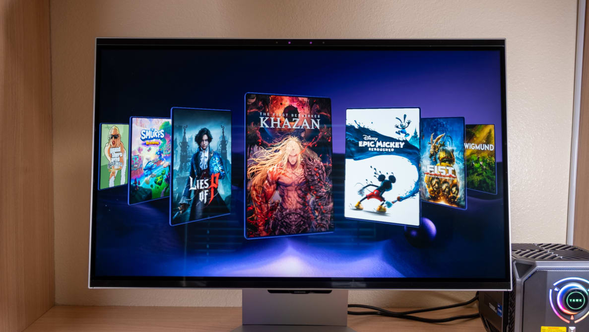 A 3D gaming monitor sits on a desk with video games gallery on its screen