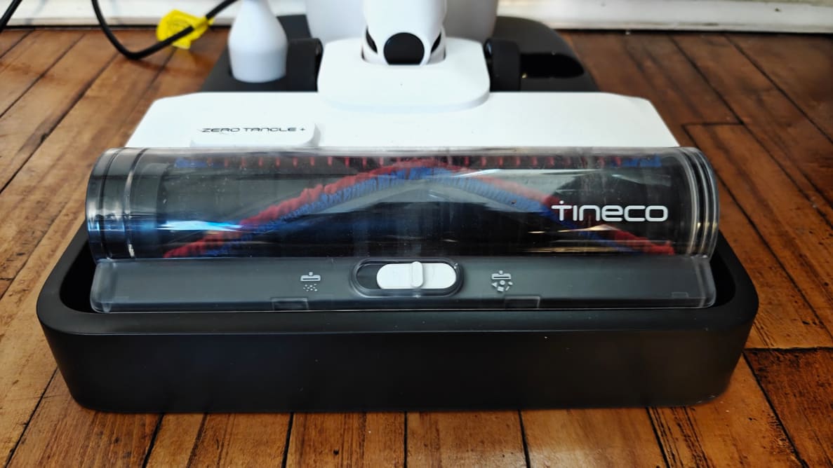 A Tineco vacuum head sits on its base on a wooden floor